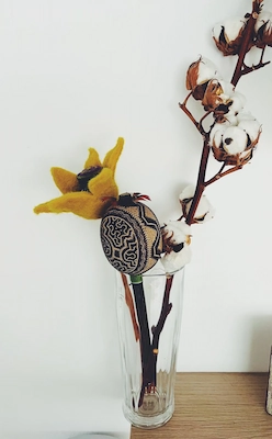 suska Staklena vaza s grančicama pamuka i ručno izrađenom ukrasnom šuškalicom s prirodnim motivima, postavljena na drvenoj površini uz bijelu pozadinu.